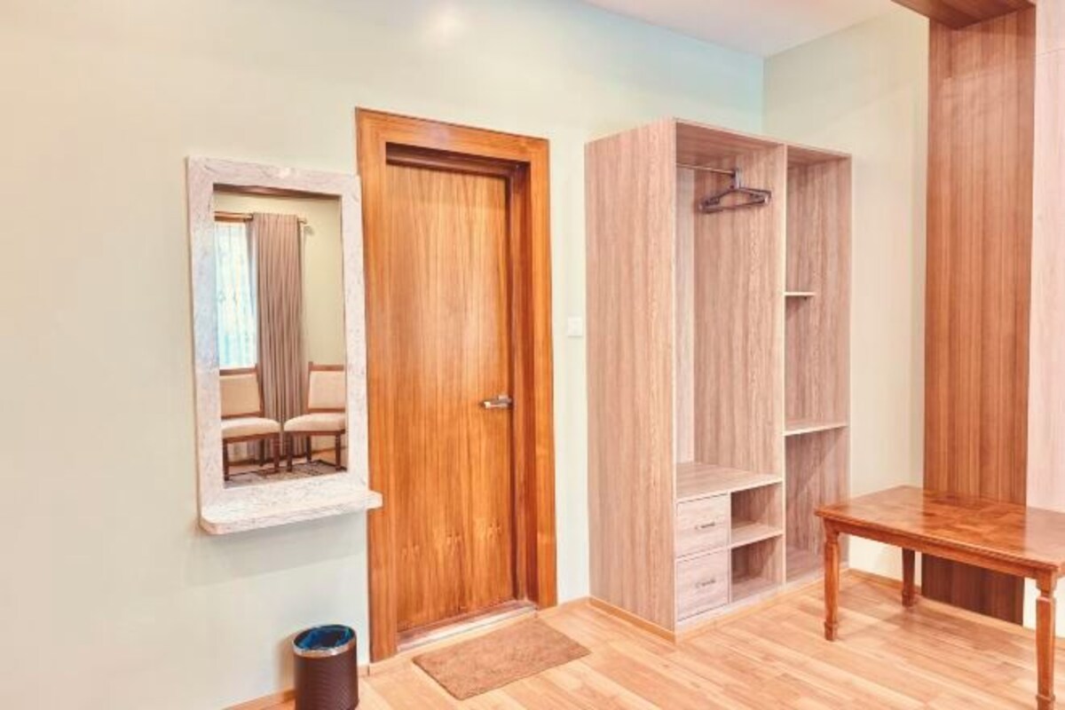 A room with a wooden door, a mirror, a wooden table, and a wardrobe.