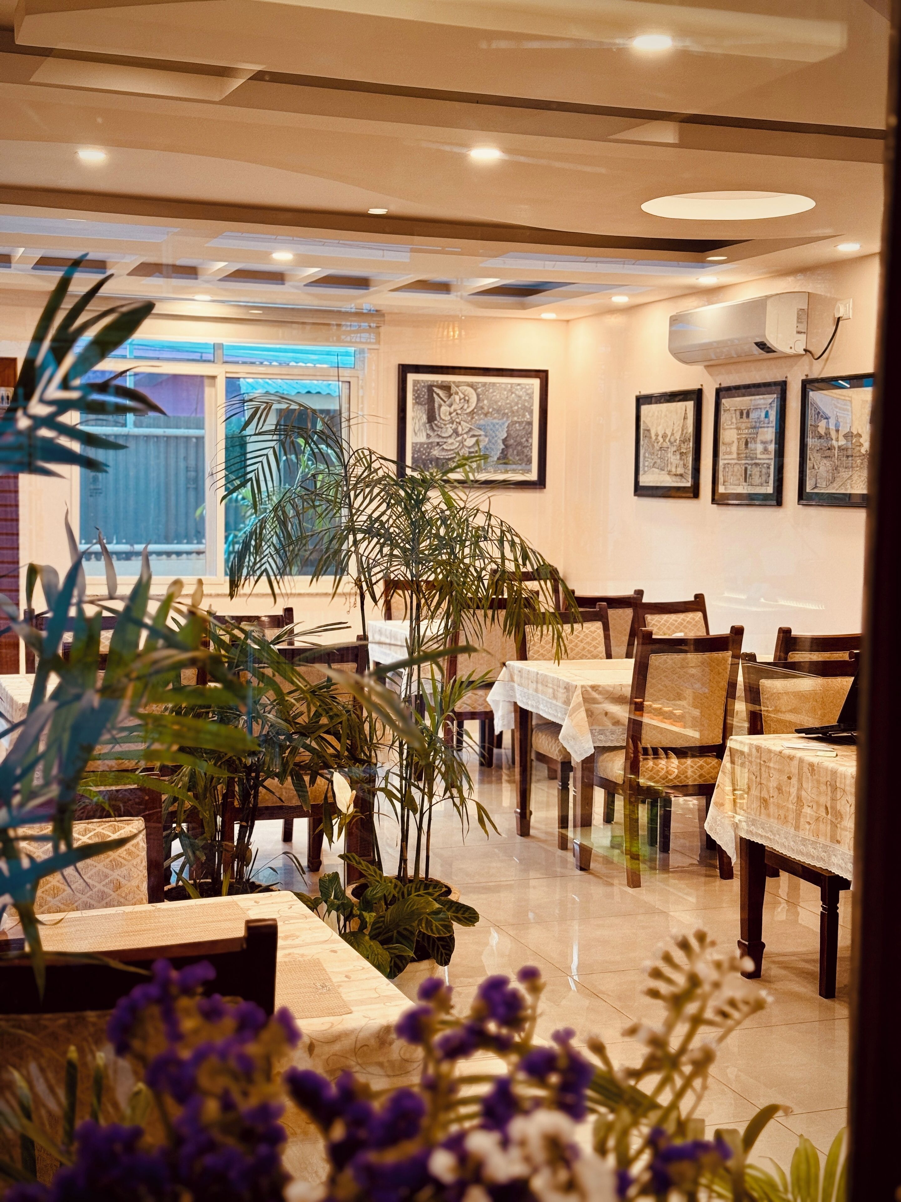 A dining area with tables, chairs, and potted plants.