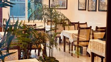 Un comedor con mesas, sillas y plantas en macetas.
