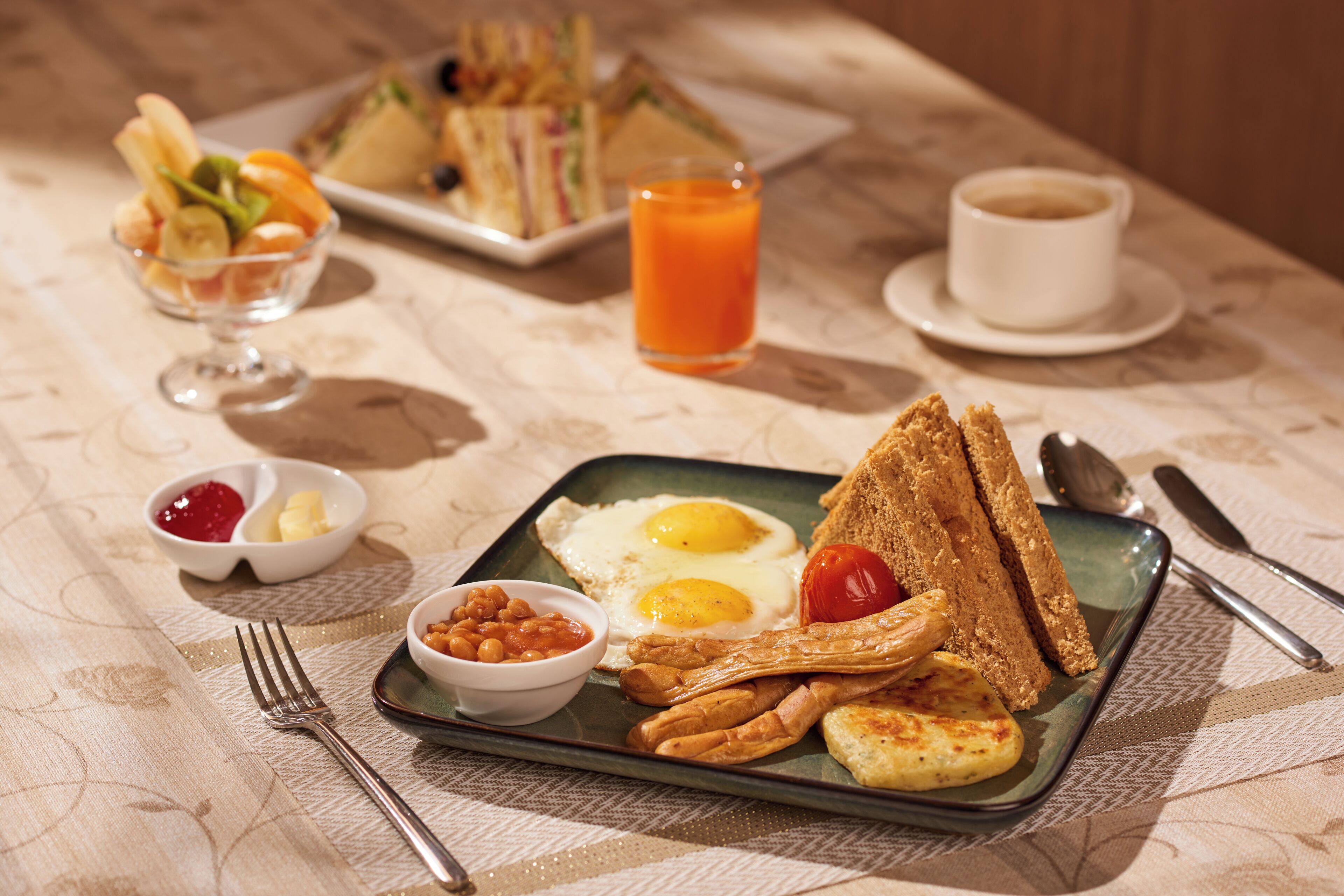 A breakfast plate with eggs, toast, beans, and a small bowl of jam.