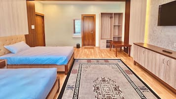 A bedroom with two beds, a wardrobe, a TV, and a small table.
