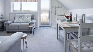 Una habitación acogedora con sofá, una mesa de comedor y una litera.