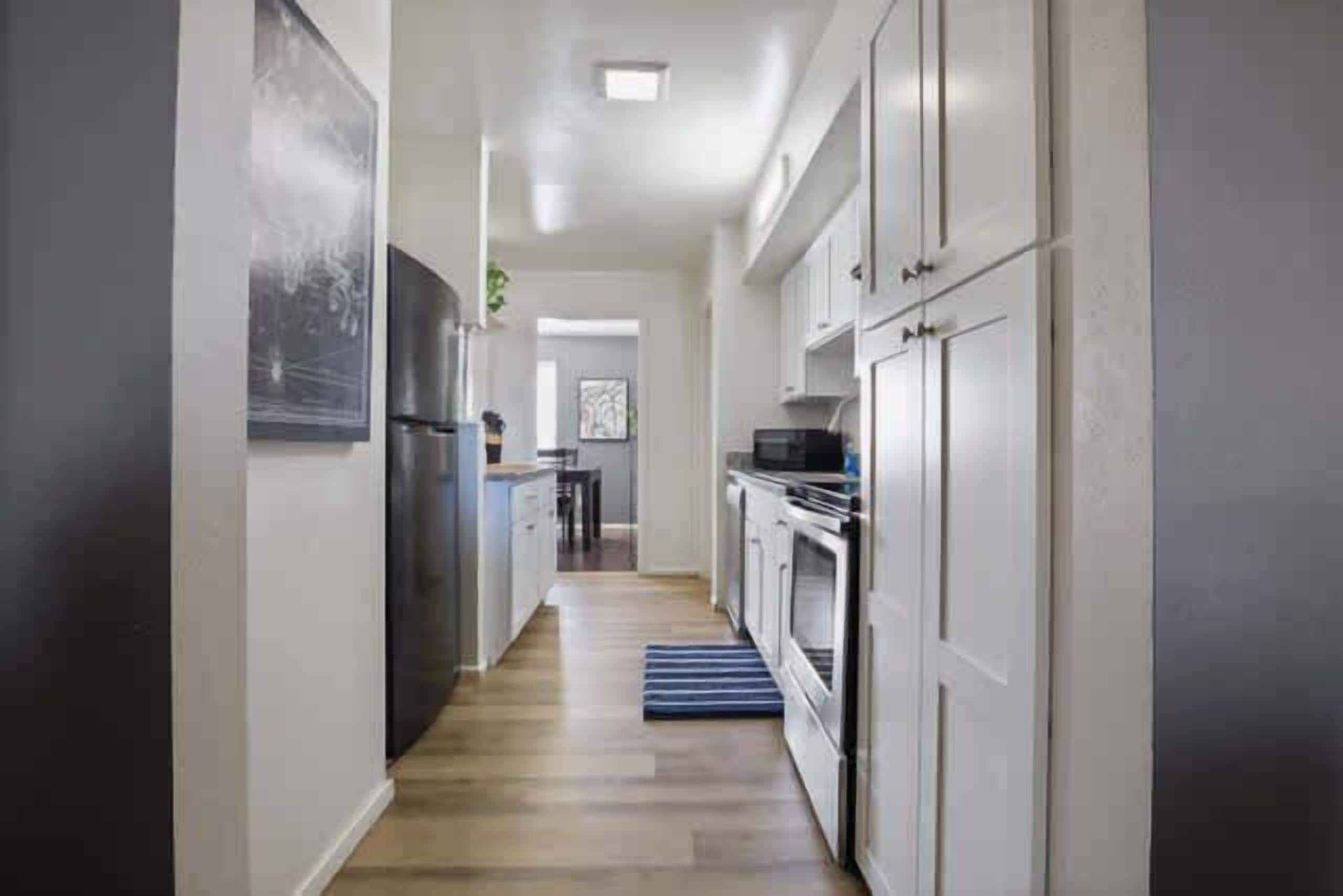 A narrow hallway with a refrigerator, oven, and cabinets.