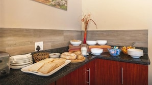 A breakfast buffet with bread, pastries, and fruit. - Oak Lodge Guesthouse (Makhanda)