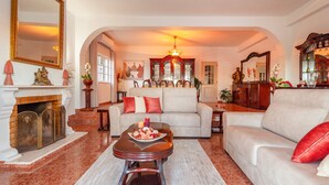 A spacious living room with a fireplace, a large mirror, and a dining area with a chandelier. - Villa Monchique Royal (Monchique)