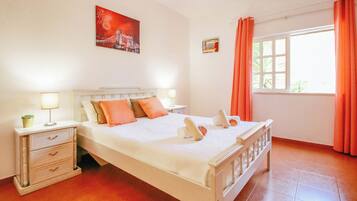 Quarto bem arrumado com cama, mesas de cabeceira e janela com cortinas.