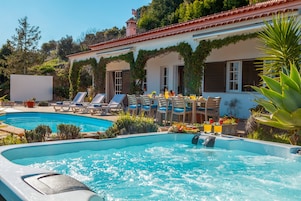 Un área de piscina con sillones reclinables, un jacuzzi y un comedor con mesas al aire libre.