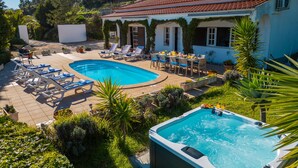 A pool area with lounge chairs, a hot tub, and a dining table set outdoors. - Villa Monchique Royal (Monchique)