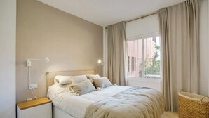 A bedroom with a bed, bedside table, lamp, and a window with curtains. - Coastal Retreat-sleeps 8, Sea View, Pool & Parking (Estepona)