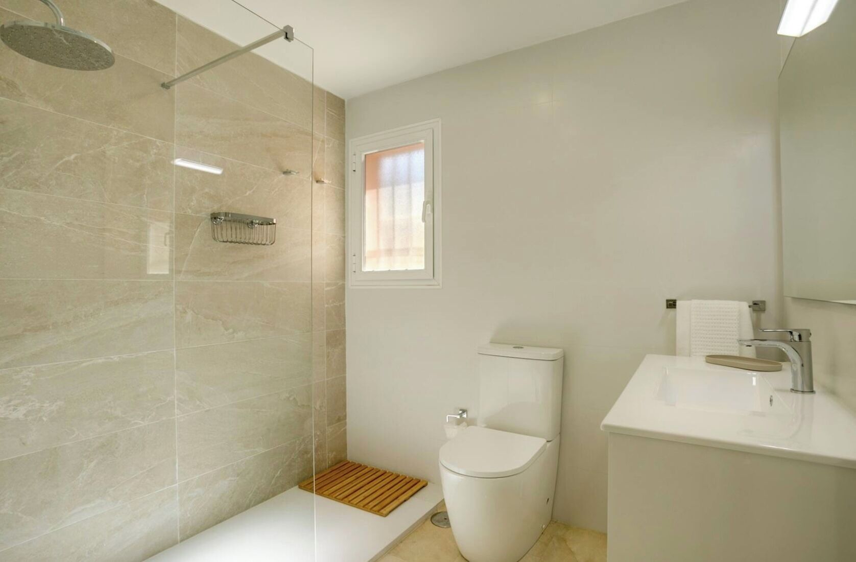 Ein modernes Badezimmer mit einer Duschkabine, einer Toilette und einem Waschbecken mit Spiegel darüber.