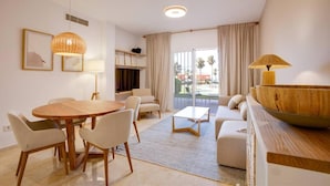 A modern living room with a round wooden table, white chairs, a sofa, and a large wooden bowl. - Coastal Retreat-sleeps 8, Sea View, Pool & Parking (Estepona)