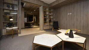 Een moderne kantoorruimte met open kasten, een ronde tafel met een lamp en een zwarte stoel.