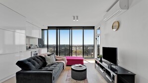 Een moderne woonkamer met een bank, voetenbankje en een flatscreen televisie.