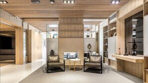 Een modern interieur met een centrale zithoek, houten lambrisering en inbouwkasten.