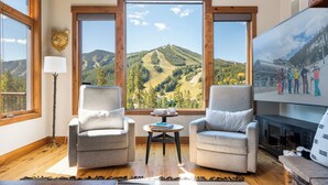 Una habitación acogedora con dos sillones, una mesita y un amplio ventanal con vistas a la montaña.