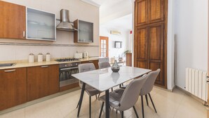 A modern kitchen with wooden cabinets, a gas stove, and a dining area with a table and chairs.