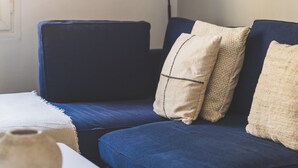 A modern living room with a blue sofa, a white table, and a woven floor lamp.