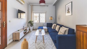 A modern living room with a blue sofa, a white coffee table, and a wooden cabinet.