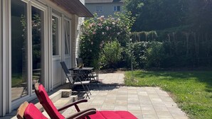 A patio with two red lounge chairs, a table, and a white decorative plate. - Newly adapted vacation apartment in the heart of Gemünd (Schleiden)