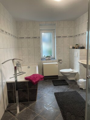 A modern bathroom with a bathtub, toilet, and sink.
