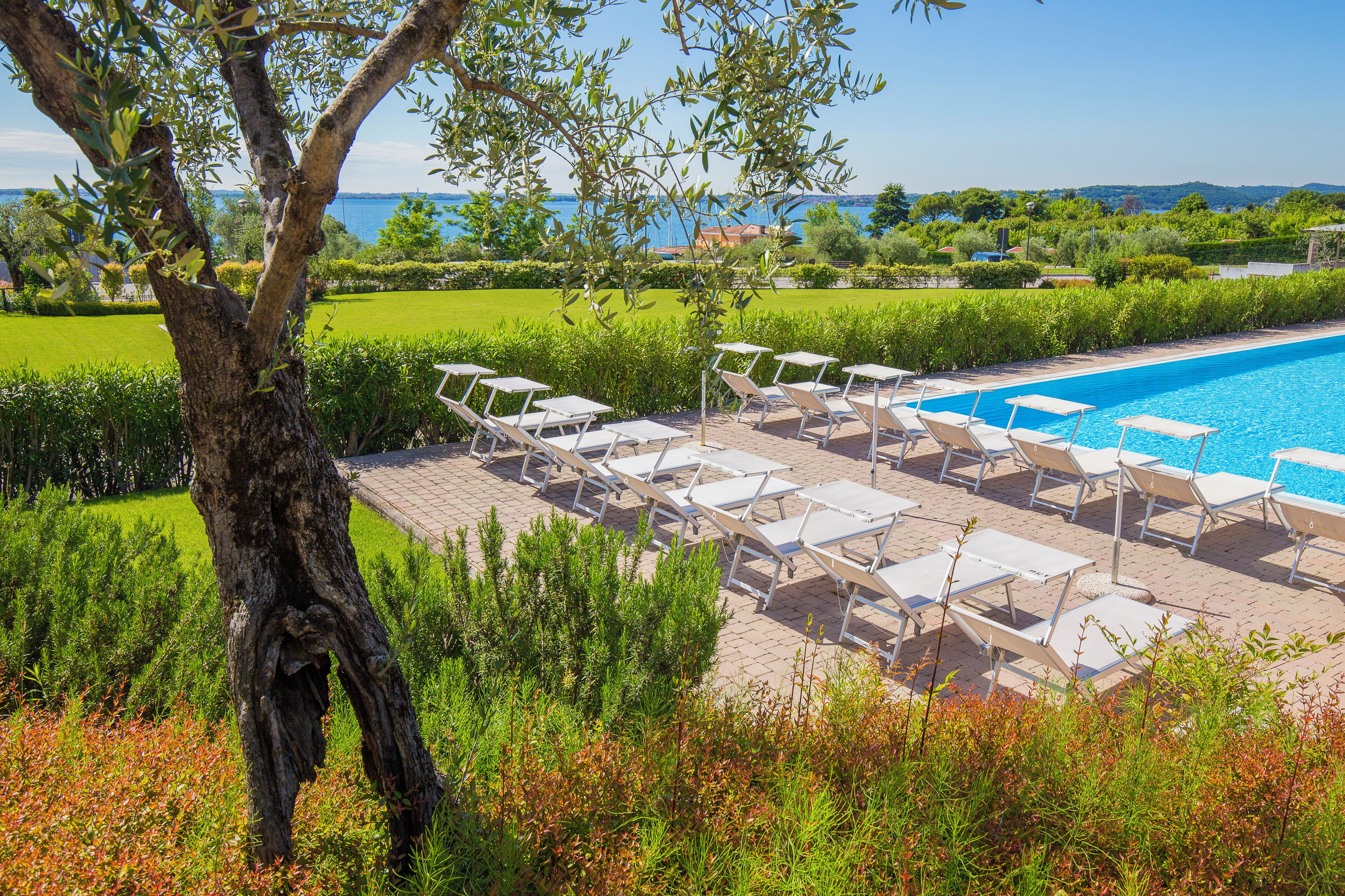 A poolside area with lounge chairs and a view of a lake.