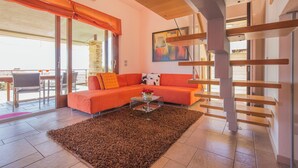 A modern living room with a sofa, a glass coffee table, and a staircase. - Marina Loft (Moniga del Garda)