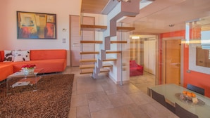 A modern living room with a staircase, orange sofa, and a glass coffee table. - Marina Loft (Moniga del Garda)