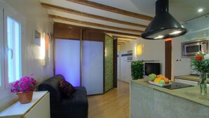 A modern kitchen with a central island, wooden beams on the ceiling, and a black pendant light.