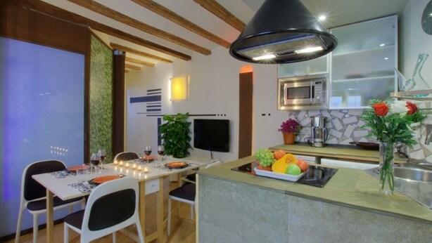 A modern kitchen with a central island, a dining area with a table and chairs, and a built-in microwave.