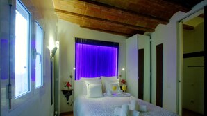 A bedroom with a bed, a window, a curtain, and a mirror.