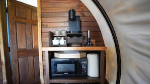 Una cocina compacta con microondas, cafetera y estantes de almacenamiento.
