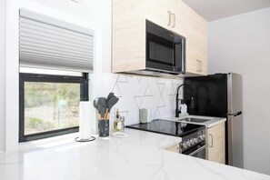 Een moderne keuken met een magnetron, fornuis en koelkast.