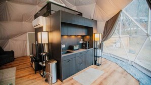 Une tente équipée d’un coin cuisine, d’un canapé et d’une lampe.