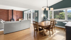 A modern living room with a wooden dining table, grey sofa, and a brick fireplace. - Home in Stowe with beautiful view of mountains

 (Stowe)