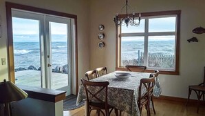 Ein Essbereich mit großem Tisch und Stühlen, einer Kronleuchter und Meerblick durch große Fenster.