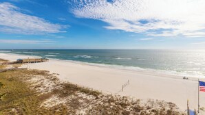 Ein Strand mit sandigem Ufer, einem Steg und einer amerikanischen Flagge.