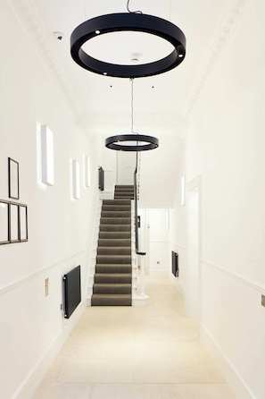 Stunning interior space with a central staircase, framed artwork, and sleek lighting fixtures.