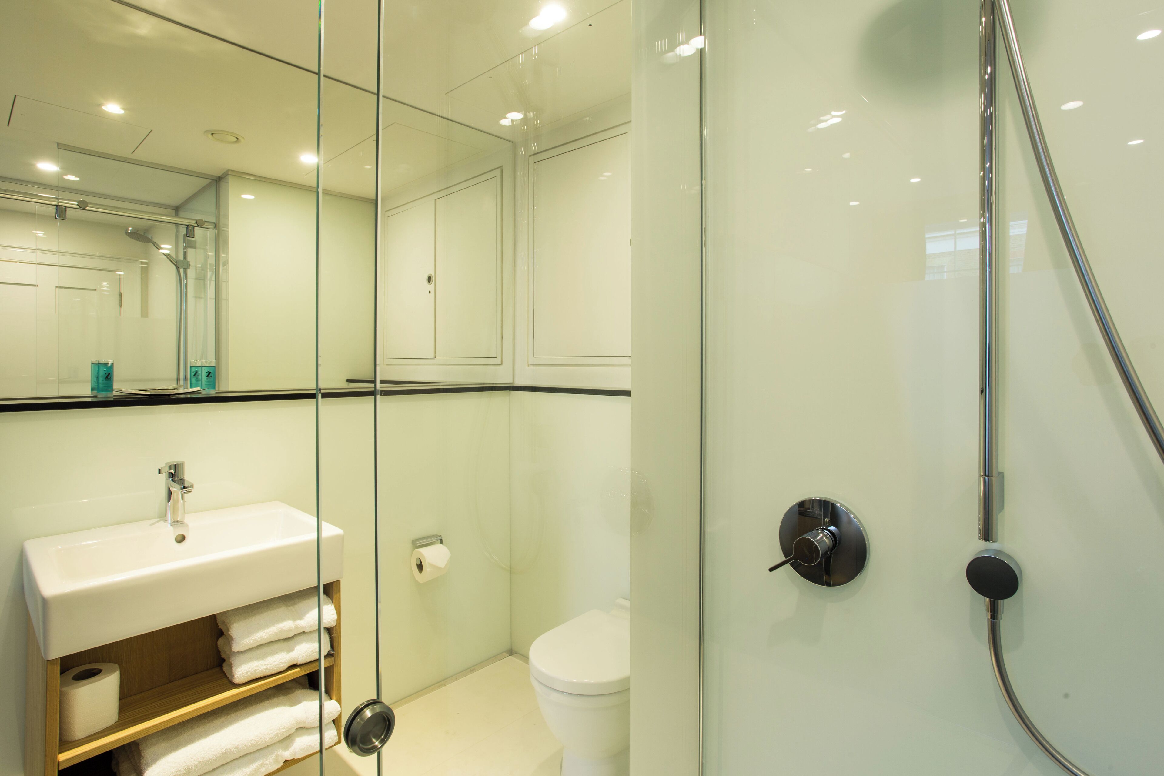Une salle de bain moderne avec une douche à parois de verre, un lavabo avec un miroir et des toilettes.