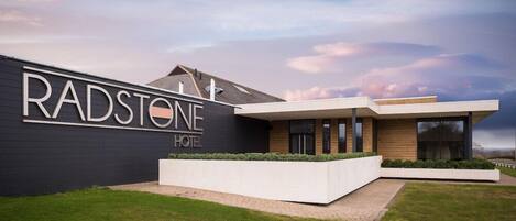 A modern Radstone Hotel with a sleek facade, large windows, and a well-maintained lawn.
