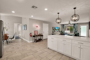 A modern kitchen with white cabinets, a dining area with a table and chairs, and pendant lighting. - Rejuvenating Palm Springs Hideout (Palm Springs)