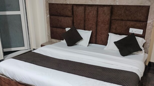 Una cama bien hecha con ropa de cama blanca y marrón oscuro, una pared con diseño de mármol y un ventilador de techo.