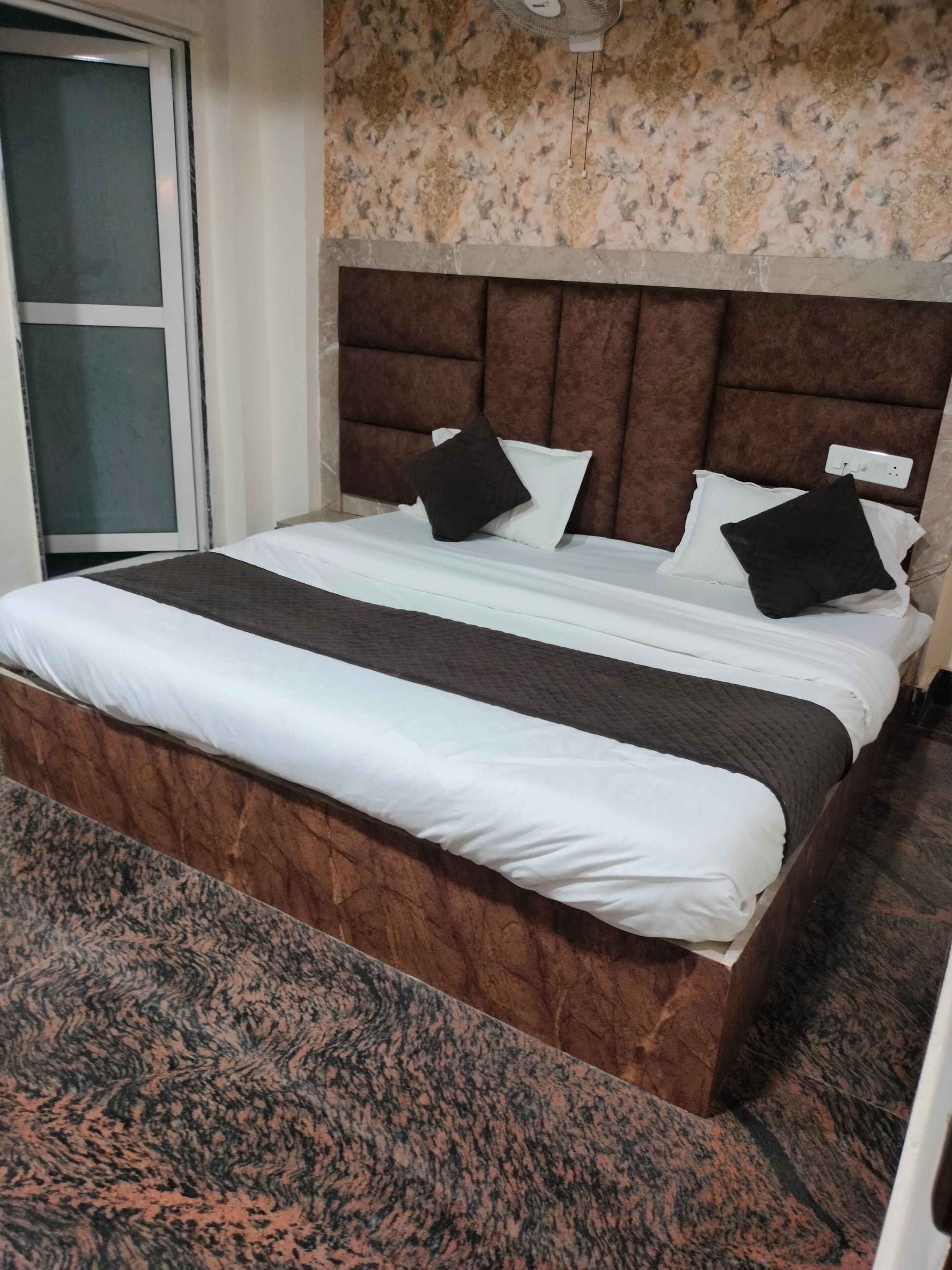 Ein Hotelzimmer mit einem großen Bett, einer Kopfteil und einem Teppichboden.