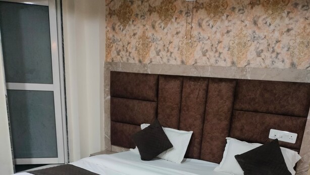 A hotel room with a large bed, a headboard, and a carpeted floor. - Hotel Kaka Inn  (Ajmer)