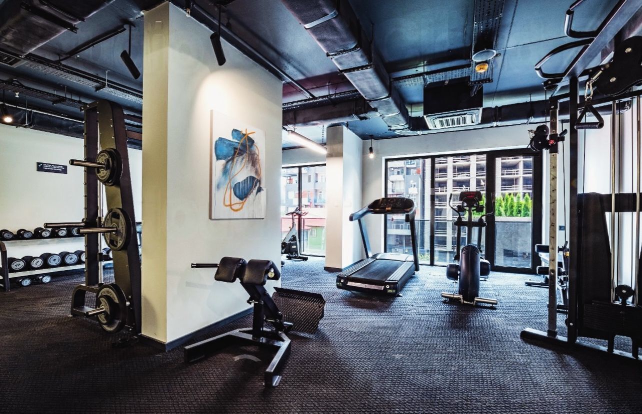 Una palestra con attrezzatura per sollevamento pesi, tapis roulant e un'ampia vetrata.