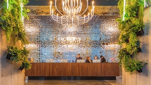 A reception area with a wooden desk, multiple people seated, and a decorative wall with plants and lights. - Nova Concierge (Batumi)