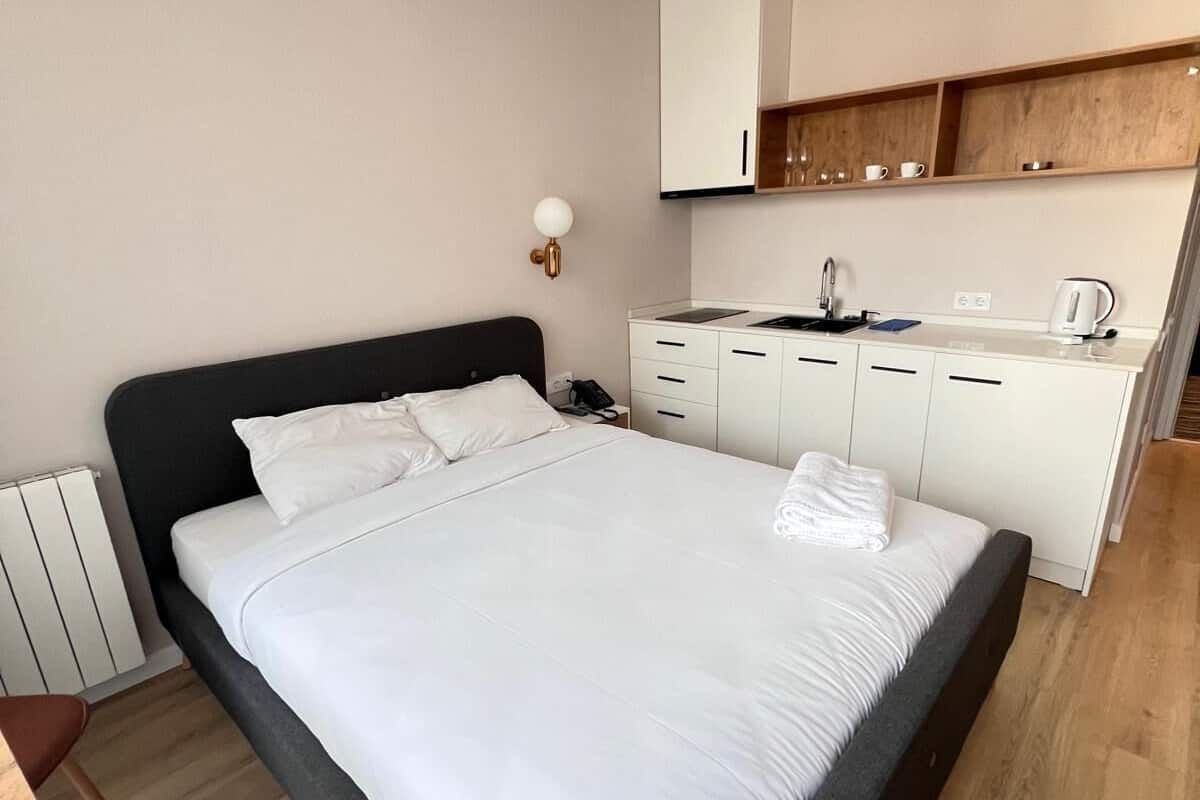 Una habitación de hotel moderna con una cama grande, una pequeña kitchenette y suelo de madera.