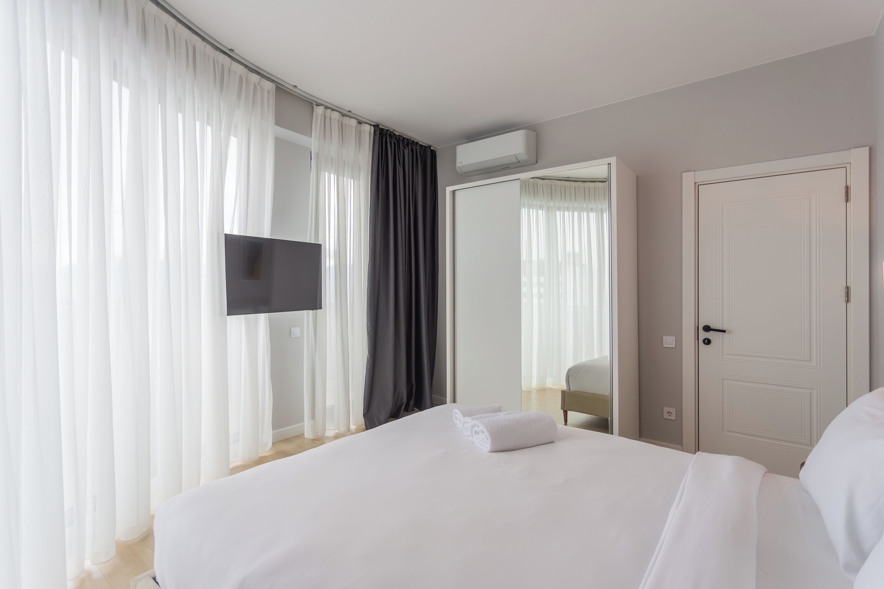 Une chambre d’hôtel avec un grand lit, un téléviseur à écran plat, une armoire et une porte.