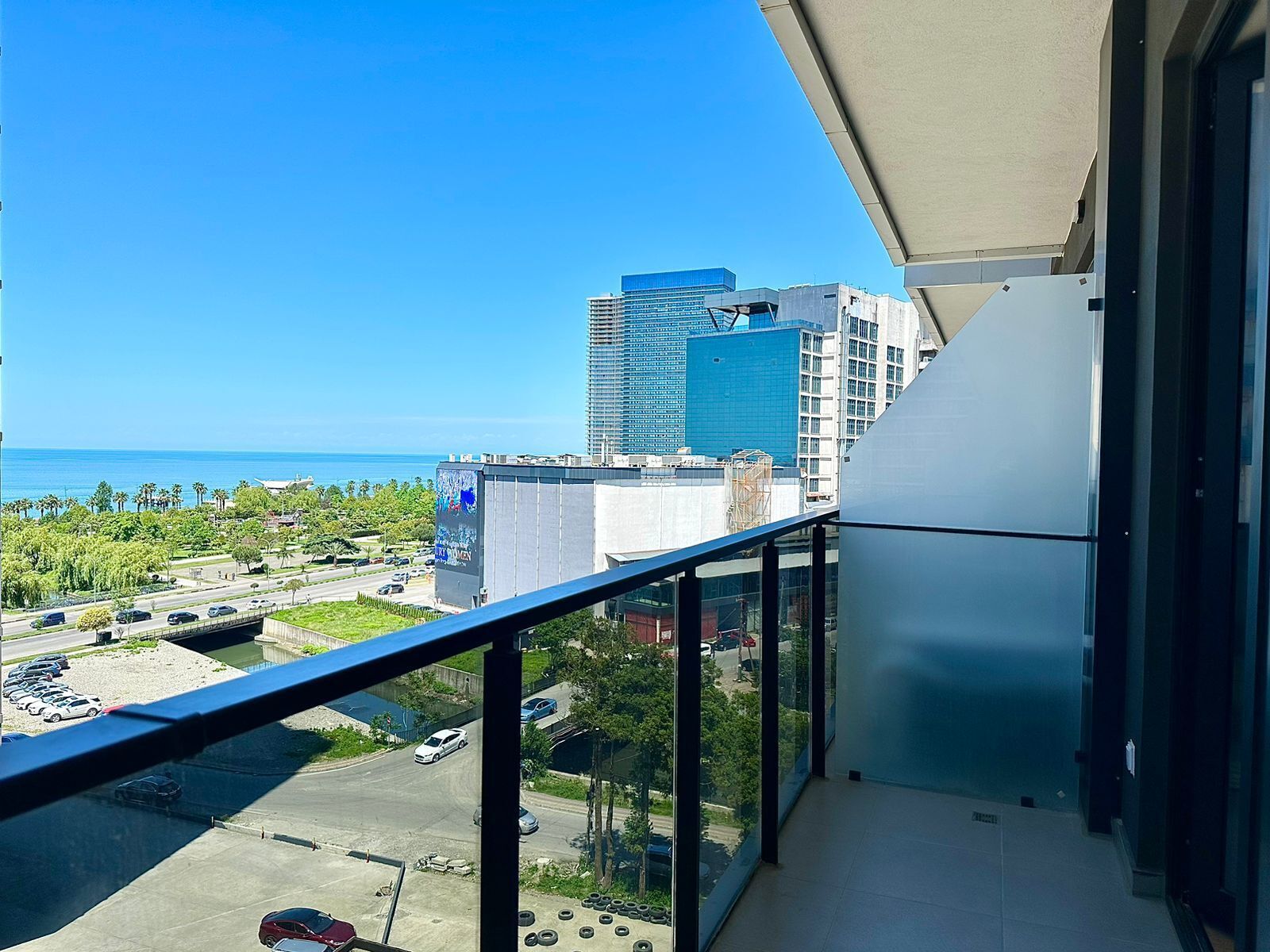 A balcony with a view of a parking lot, a road, and buildings in the background.