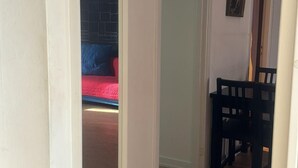 A hallway with a bed in the background, a door, and a dining area with chairs. - Apartment Close to Stockholm City (Hägersten)