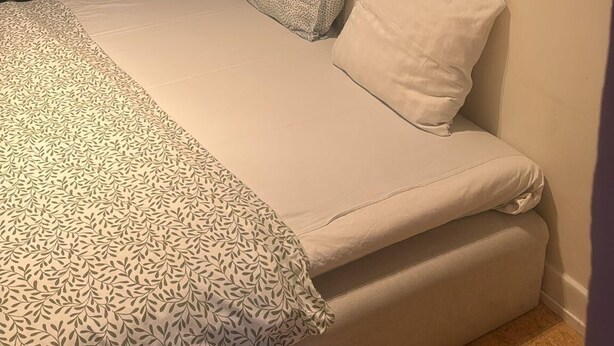 A bedroom with a bed, patterned curtains, a tropical-themed wall mural, and a pillow. - Apartment Close to Stockholm City (Hägersten)